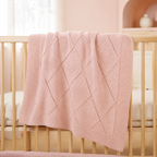 Couverture bébé rose poudré en maille à cœurs dans un lit bébé