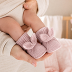 Chaussons lapin rose poudré portés par un bébé