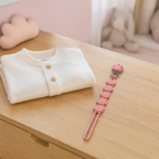 Attache-tétine renard rose en silicone dans une chambre de bébé
