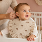 Parent attachant un bavoir arcs-en-ciel à un bébé