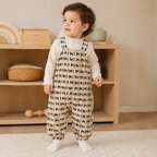 Jeune enfant debout portant la salopette beige à motif noir