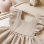 Détail des volants et du tissu de la robe bébé beige