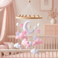 Mobile bébé lune, nuages roses et étoiles en feutrine dans une chambre de bébé