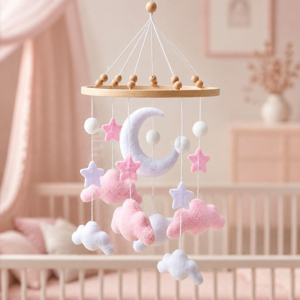 Mobile bébé lune, nuages roses et étoiles en feutrine dans une chambre de bébé